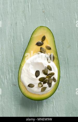 An avocado filled with Greek yoghurt and pumpkin seeds Stock Photo