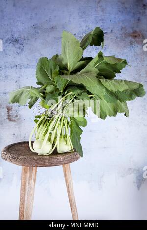 Fresh kohlrabi with leaves on a wooden stool Stock Photo