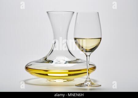 A glass carafe and a glass of white wine on a white surface Stock Photo