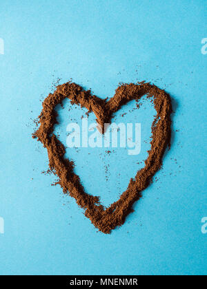 Heart made with grinded coffee powder over blue background Stock Photo