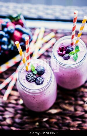 Berry smoothies in two screw-top jars with straws Stock Photo