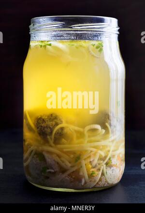 Chicken soup with liver dumplings and egg noodles in a glass jar Stock Photo