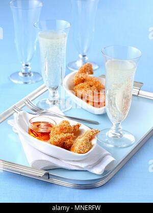 Fried sesame seed prawns with a chilli dip and glasses of champagne Stock Photo