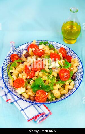 Pasta with steamed tomatoes, feta cheese, olives and rocket Stock Photo