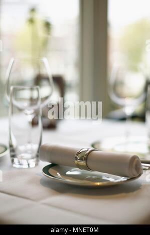 A fabric napkin on a plate and empty glasses on a table in a restaurant Stock Photo