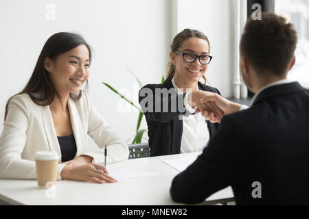 Businessman shaking hand of female coworker during company meeti Stock Photo