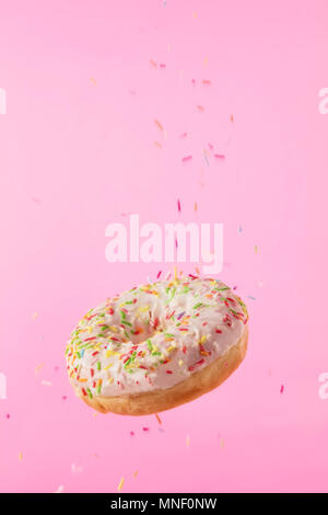 Flying sweet donut isolated on pink background. Concept of low gravity food in freeze motion effect. High resolution image Stock Photo