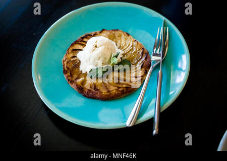 Apple tart with vanilla ice cream on dark background.Sweet delicious cake with ice cream and with caramel sauce. Stock Photo