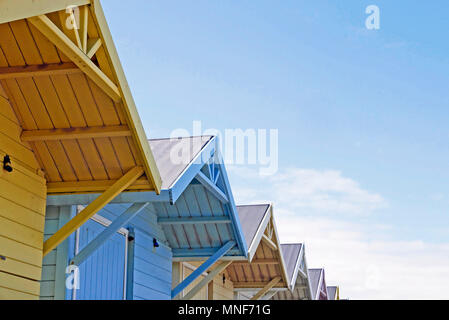 Apex of roofs of row of colourful beach huts against blue sky Stock Photo