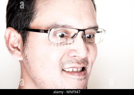 Face of Asian man with eyeglasses for near sighted feeling very angry and mad. His eyes is wided open and gritting his teeth. Stock Photo