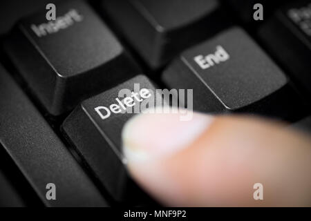 Pointing finger pressing on delete button on PC keyboard. Stock Photo