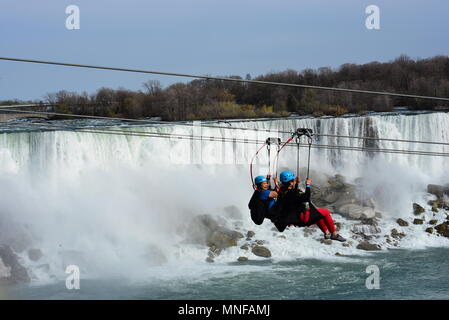 Two females ride WildPlay's Mistrider Zipline to the Falls above Niagara River in Niagara Falls, Ontario, Canada. Stock Photo