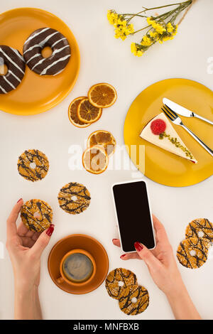 hand with smartphone and cookies Stock Photo