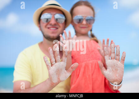 Portrait of happy father and daughter showing their hands covered in white sand Stock Photo