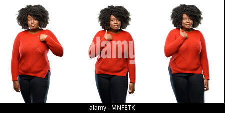 Young beautiful african plus size model happy and surprised cheering expressing wow gesture, pointing with finger isolated over white background. Coll Stock Photo