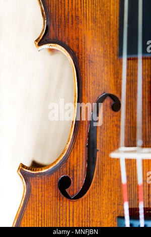 Focus on F hole in violin body belly. Top view, detaled macro with shalow depth of field on strings and bridge Stock Photo