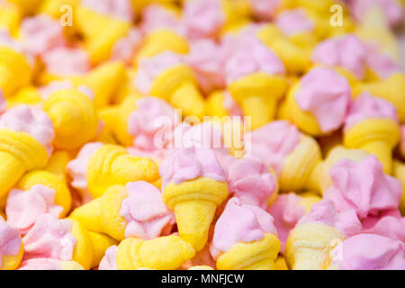 Little sweets, pink, yellow, in ice cream shapes lay flat full frame cover. Concept opaque background Stock Photo