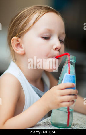 Adorable little girl drinking water from a bottle using a straw Stock Photo