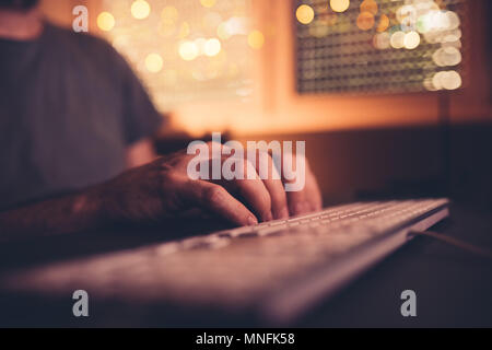 Nervous male hands tapping on desk table in dark room interior, low key with selective focus Stock Photo