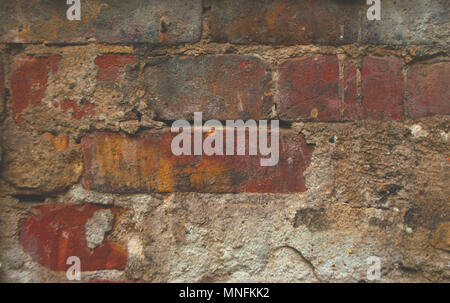 Old dark brick wall background with damaged plaster. Stock Photo