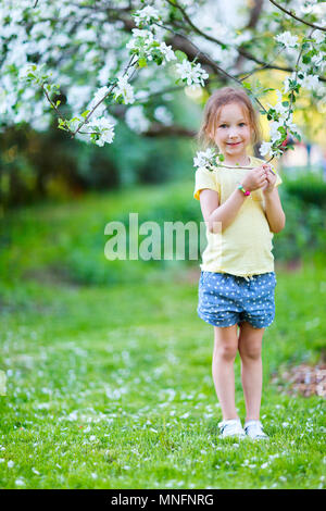 Adorable little girl in in blooming apple tree garden on spring day Stock Photo