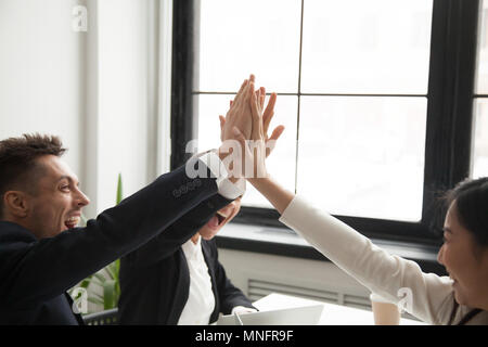 Excited colleagues giving high five reaching goal Stock Photo