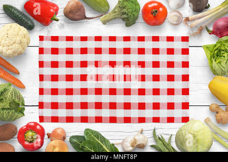 Traditional red white table cloth on kitchen table surrounded with vegetables. Stock Photo