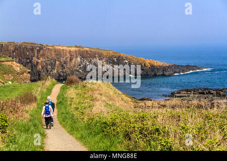 Couple walking along the Northumberland Coast Path between Howick and Craster on a sunny day in May 2018. Stock Photo