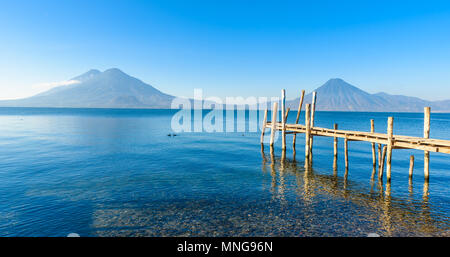Wooden pier at Lake Atitlan on the beach in Panajachel, Guatemala. With beautiful landscape scenery of volcanoes Toliman, Atitlan and San Pedro in the Stock Photo