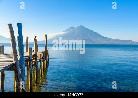 Wooden pier at Lake Atitlan on the beach in Panajachel, Guatemala. With beautiful landscape scenery of volcanoes Toliman, Atitlan and San Pedro in the Stock Photo