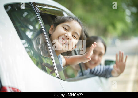 Happy Asian little girl playing on window car with mother, Family traveling on countryside Stock Photo