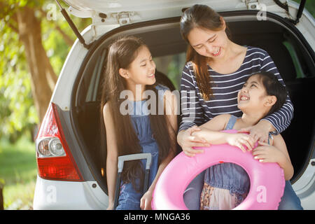 Happy Asian daughters and mother preparing for travel on vacation with mini van car Stock Photo