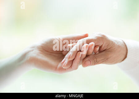 Close-up photo of young hand holding the older one Stock Photo