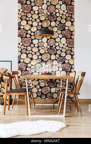 Rustic design and wooden log wall decoration in stylish modern dining room with black lamp and retro chairs Stock Photo