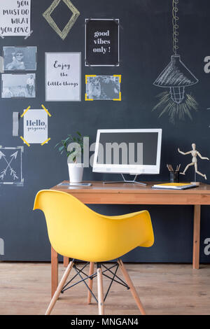 Cropped shot of an office interior with a minimalistic wooden desk and yellow chair Stock Photo