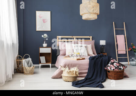 Small decorative wicker baskets in a room with big wooden bed Stock Photo