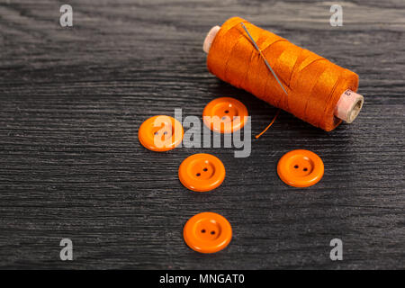 spool of threads and buttons on a wooden background Stock Photo