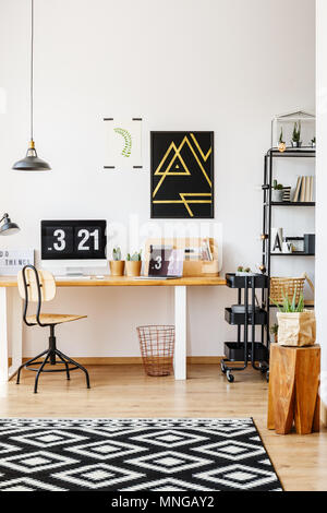 Natural decor of scandinavian study desk workspace with wooden furniture, retro chair, plants, lamps and computer with digital desktop clock Stock Photo