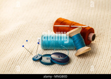 colored thread and buttons on white knitted fabric Stock Photo