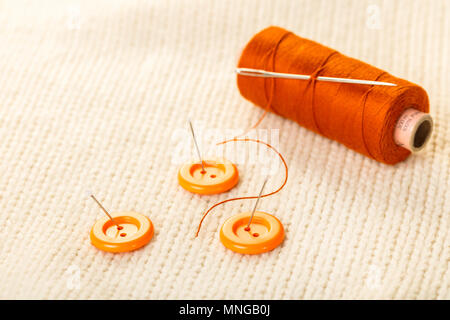 colored thread and buttons on white knitted fabric Stock Photo