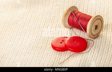 colored thread and buttons on white knitted fabric Stock Photo