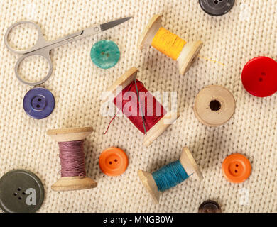 colorful threads and buttons on white knitted fabric Stock Photo
