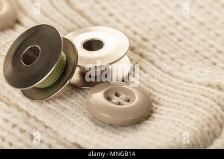 spool of thread closeup on white knitted clothes Stock Photo