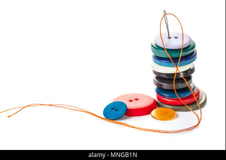Needle with orange thread and buttons on a white isolated background Stock Photo