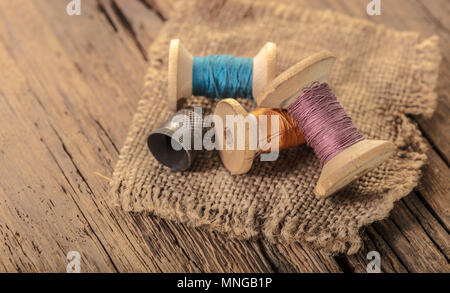 colored threads and thimble on wooden background Stock Photo