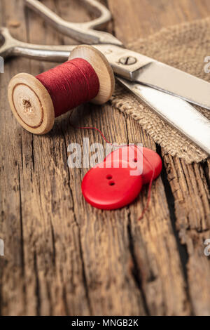 red thread with buttons and scissors, wooden background Stock Photo
