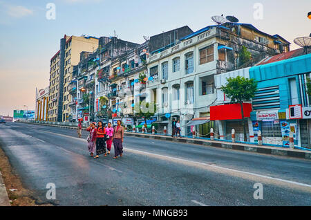 YANGON, MYANMAR - FEBRUARY 16, 2018: The group of pedestrians cross the Pansodan street bridge with a view on shabby residential quarter on background Stock Photo