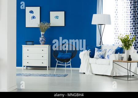 Sofa, chair, lamp and chest of drawers in blue and white living room Stock Photo