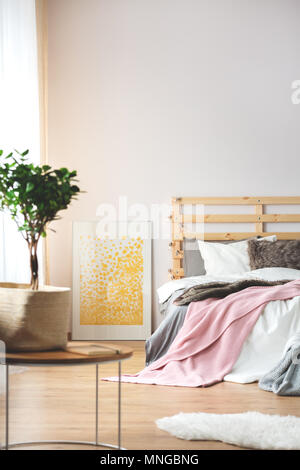 Plant and yellow poster in cozy modern bedroom Stock Photo