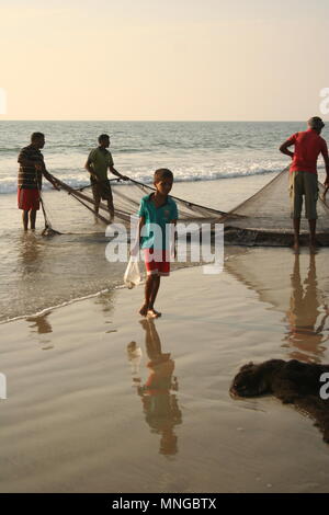 India Boy with Fish in a bag and Fishermen, Colva Beach, Goa Stock Photo